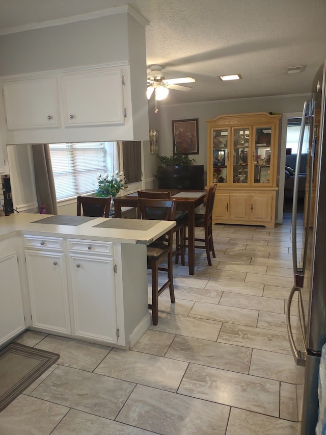 2039 Lovers Ln, Shreveport, LA 71105 - kitchen featuring white cabinetry, a ceiling fan, a peninsula, light countertops, and a textured ceiling