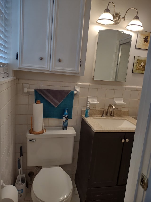 bathroom with vanity, tile walls, toilet, and a wainscoted wall