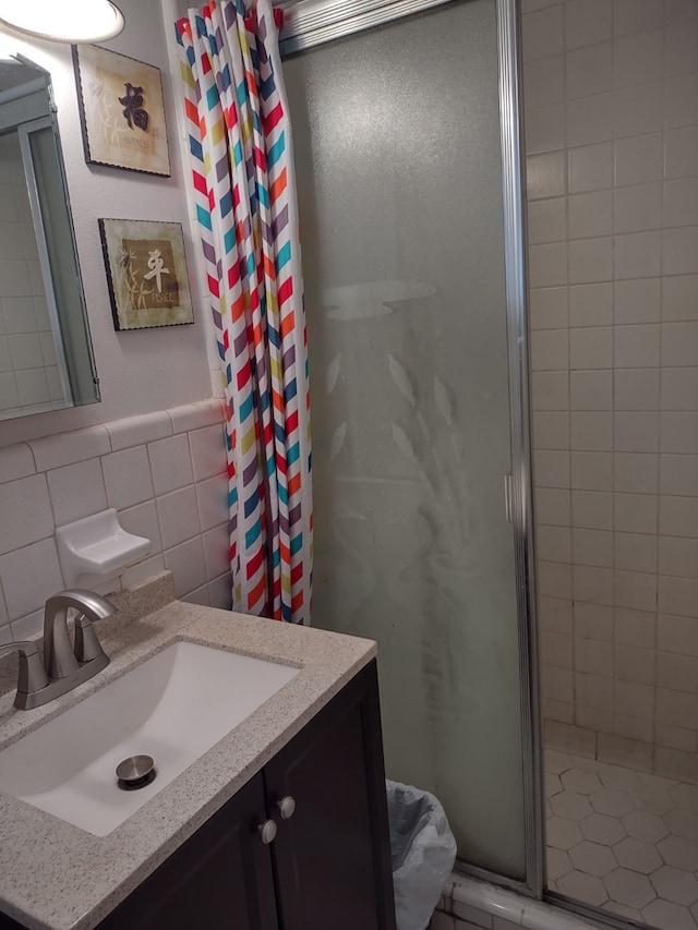 full bath with vanity, tile walls, and a shower stall