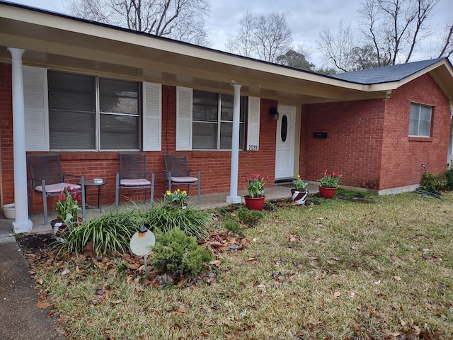 single story home with brick siding, a porch, and a front yard