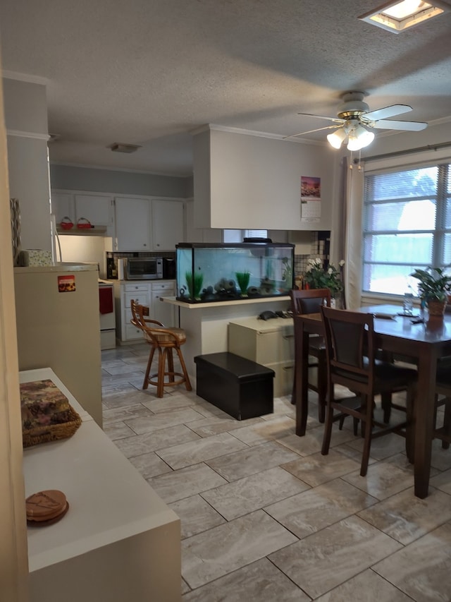 dining area with a textured ceiling, ornamental molding, visible vents, and ceiling fan