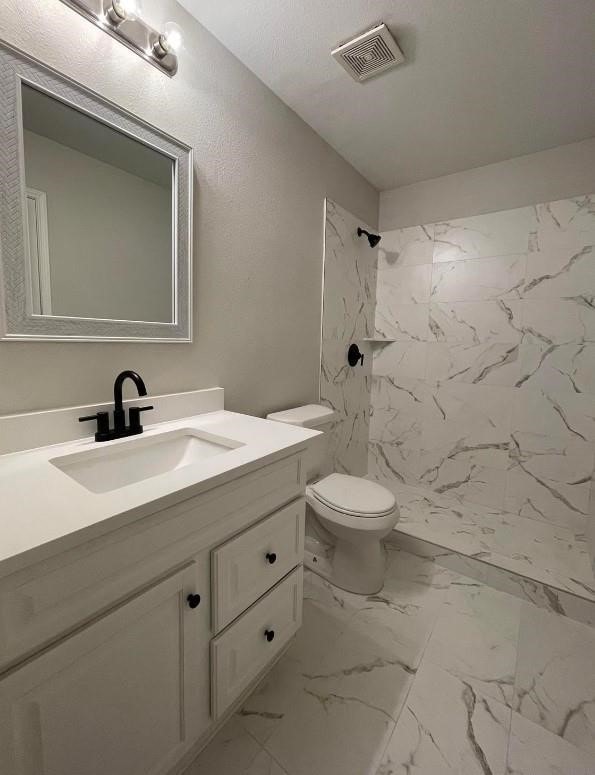 bathroom with vanity, visible vents, a stall shower, toilet, and marble finish floor