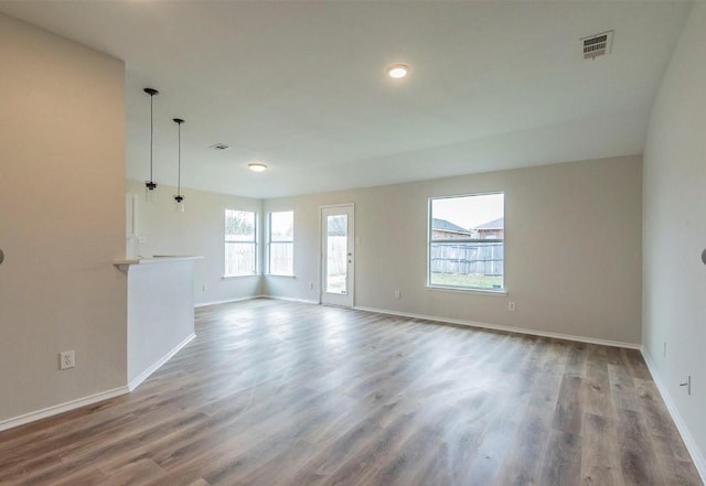 empty room featuring wood finished floors, visible vents, and baseboards