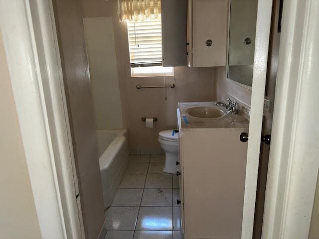 bathroom with vanity, tile patterned floors, toilet, and a bath