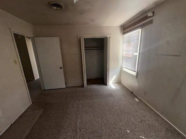 unfurnished bedroom with visible vents, carpet floors, and baseboards