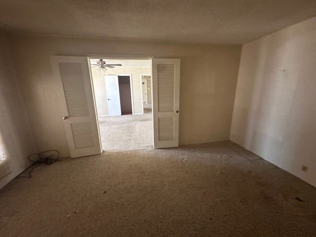 carpeted empty room with a textured ceiling and ceiling fan