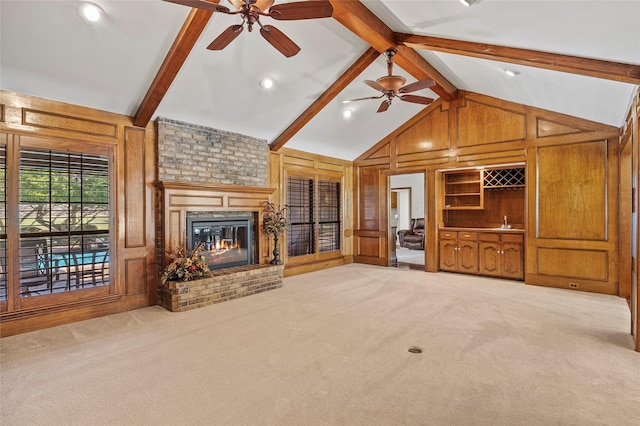 unfurnished living room featuring ceiling fan, lofted ceiling with beams, wood walls, and carpet flooring