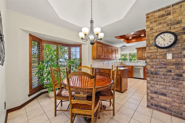 dining area featuring a raised ceiling, light tile patterned floors, baseboards, and a chandelier