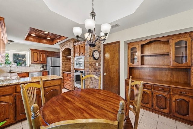 dining area with light tile patterned floors, visible vents, a chandelier, and a tray ceiling