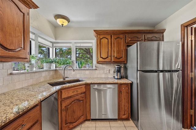 kitchen with backsplash, light tile patterned floors, brown cabinets, stainless steel appliances, and a sink