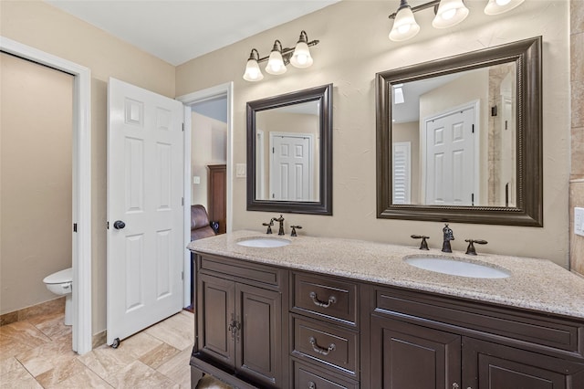 bathroom with a sink, toilet, and double vanity