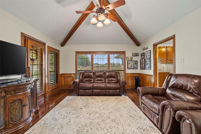 living room with wainscoting, lofted ceiling with beams, a ceiling fan, and dark wood-style flooring