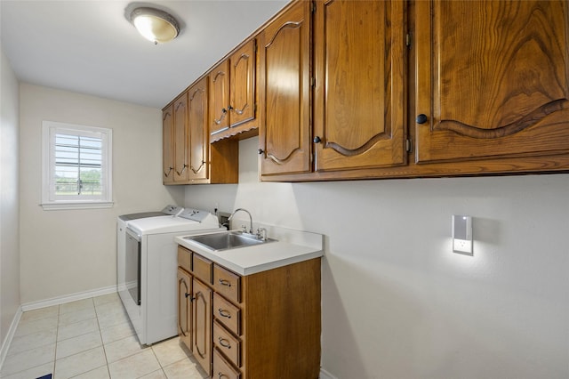 washroom featuring washing machine and clothes dryer, baseboards, light tile patterned floors, cabinet space, and a sink