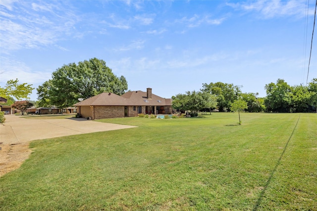 view of yard featuring an attached garage, a patio area, and driveway