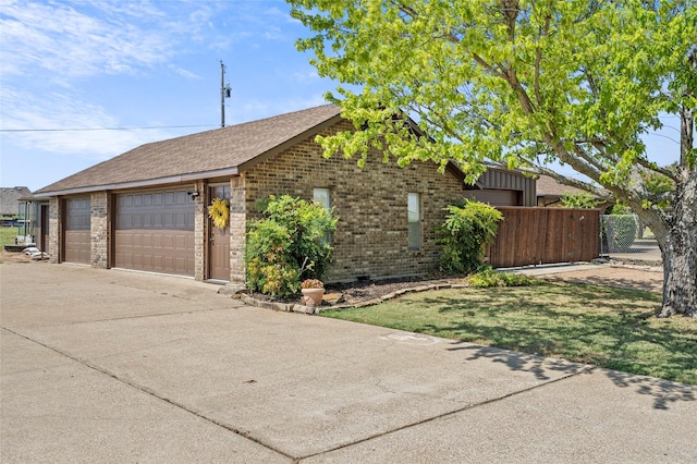 view of front facade featuring a garage, brick siding, roof with shingles, and fence