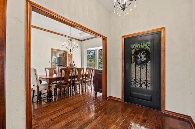 entrance foyer with baseboards, dark wood-type flooring, an inviting chandelier, and ornamental molding