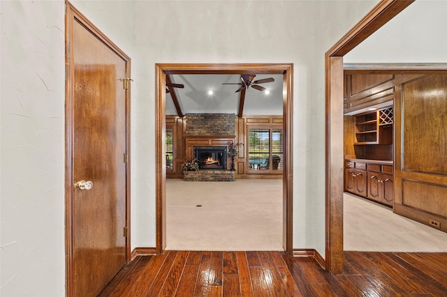 hallway featuring dark wood-type flooring, baseboards, and dark colored carpet