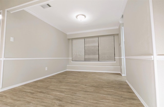 empty room featuring crown molding, wood finished floors, visible vents, and baseboards