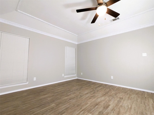 empty room featuring a ceiling fan, wood finished floors, visible vents, baseboards, and crown molding