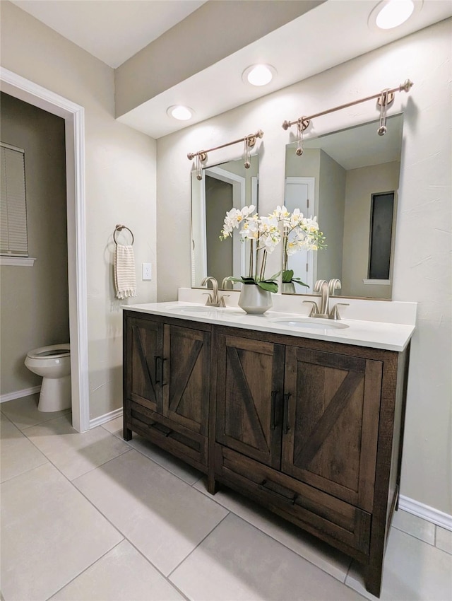 full bathroom featuring tile patterned flooring, double vanity, toilet, and a sink