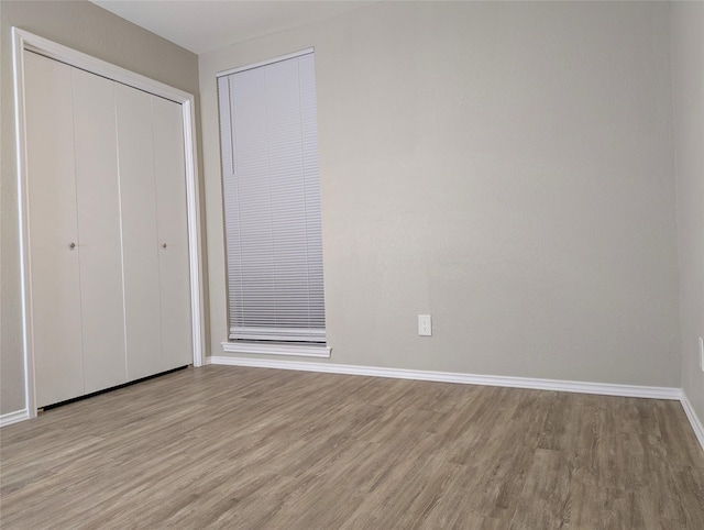 unfurnished bedroom with a closet, baseboards, and wood finished floors