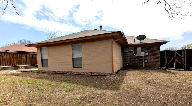 rear view of house with brick siding and fence