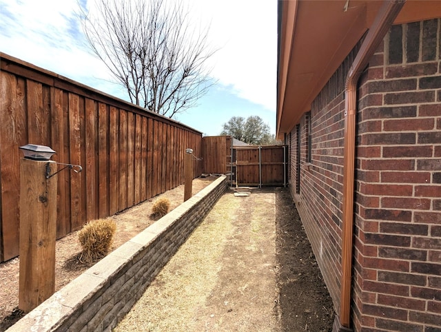 view of side of property featuring brick siding and a fenced backyard