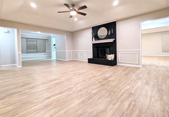 unfurnished living room featuring wood finished floors, a raised ceiling, ceiling fan, and a decorative wall