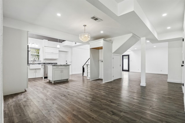 kitchen with visible vents, a kitchen island, dark wood-type flooring, open floor plan, and a sink