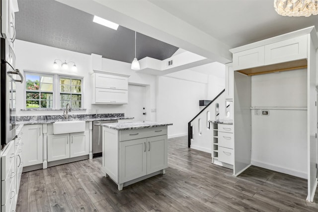 kitchen featuring a center island, light stone countertops, appliances with stainless steel finishes, and a sink