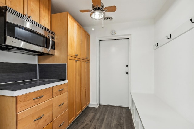 kitchen with a ceiling fan, visible vents, dark wood finished floors, light countertops, and stainless steel microwave