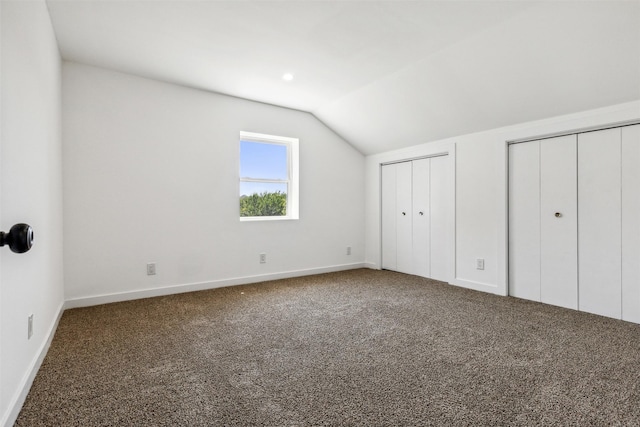 unfurnished bedroom with vaulted ceiling, baseboards, multiple closets, and carpet floors