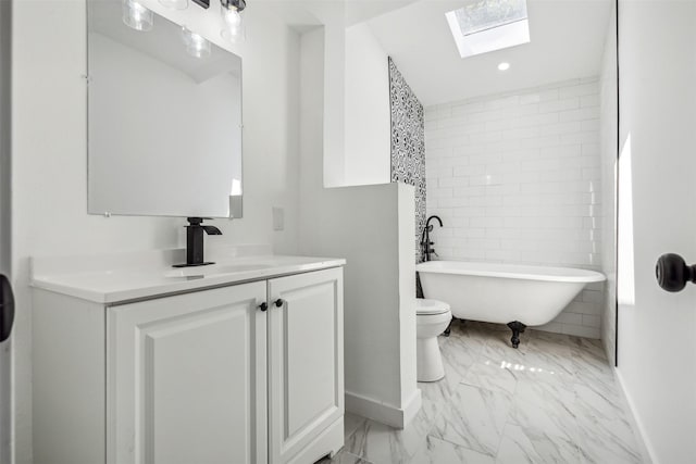 full bathroom featuring vanity, baseboards, a skylight, a freestanding tub, and marble finish floor