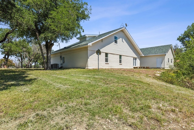 rear view of house featuring central air condition unit, a lawn, and brick siding