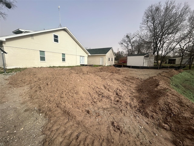 back of property with brick siding, a storage shed, and an outdoor structure