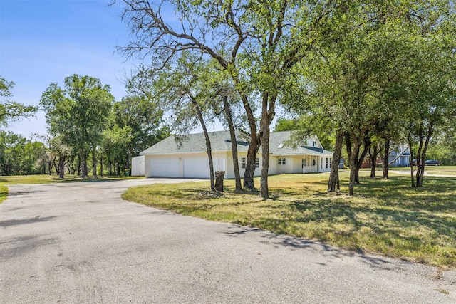 view of front of property featuring aphalt driveway, a garage, and a front yard