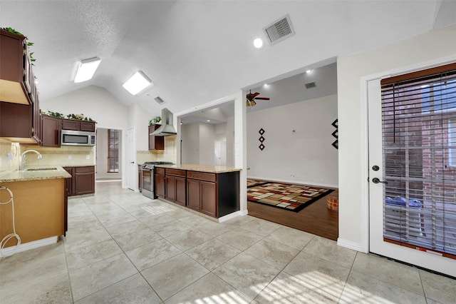 kitchen with visible vents, appliances with stainless steel finishes, wall chimney exhaust hood, light tile patterned floors, and vaulted ceiling