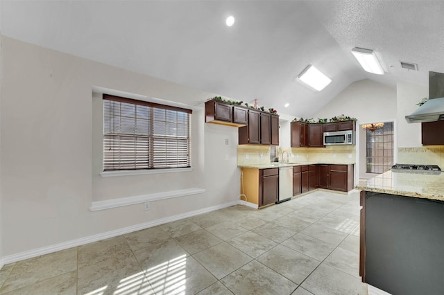 kitchen with lofted ceiling, a sink, appliances with stainless steel finishes, wall chimney exhaust hood, and tasteful backsplash