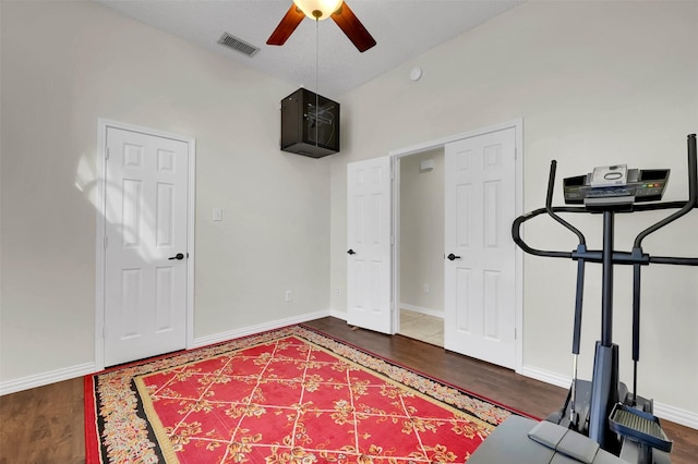 exercise area with visible vents, wood finished floors, ceiling fan, and vaulted ceiling