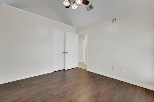 empty room with visible vents, baseboards, vaulted ceiling, wood finished floors, and a ceiling fan