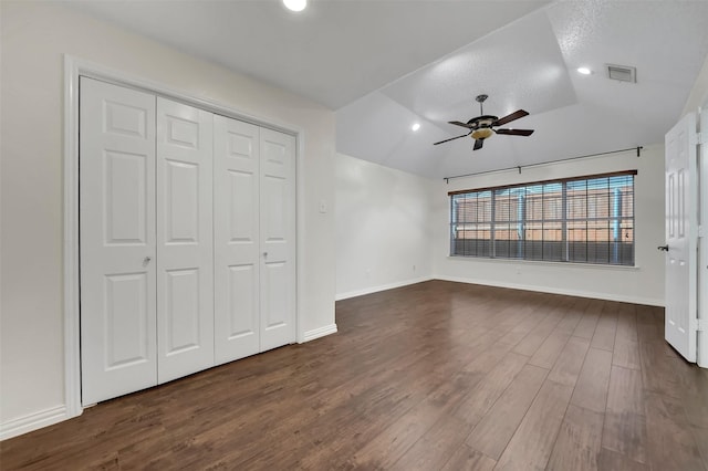 interior space with visible vents, dark wood-type flooring, baseboards, ceiling fan, and vaulted ceiling