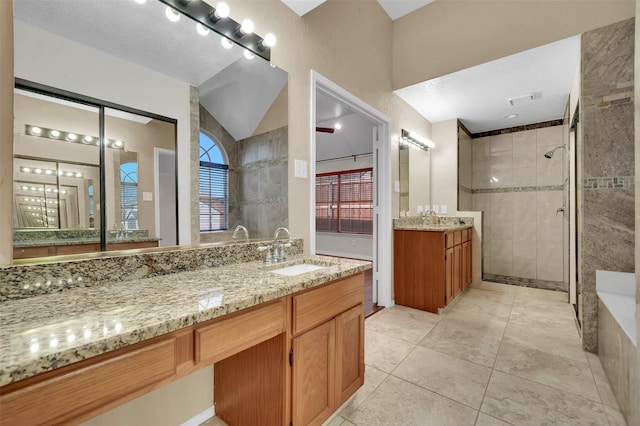 bathroom featuring a tile shower, visible vents, vanity, and lofted ceiling