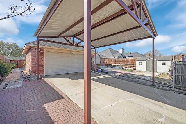 view of patio / terrace featuring fence, a shed, a residential view, an outdoor structure, and driveway