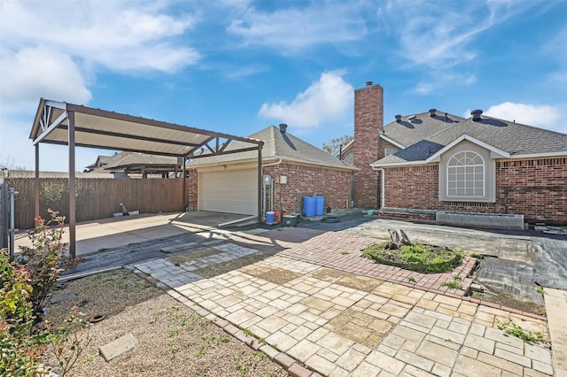 view of patio / terrace with driveway, an attached garage, and fence