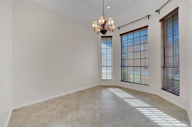 tiled spare room featuring a chandelier, a healthy amount of sunlight, and baseboards