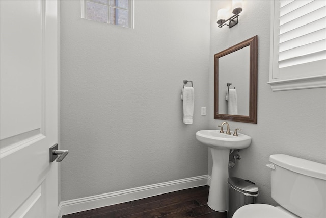 bathroom with toilet, wood finished floors, baseboards, and a textured wall