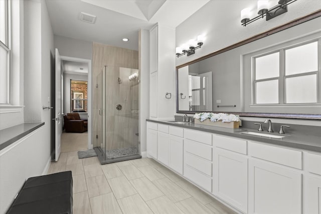 bathroom with double vanity, visible vents, a stall shower, and a sink