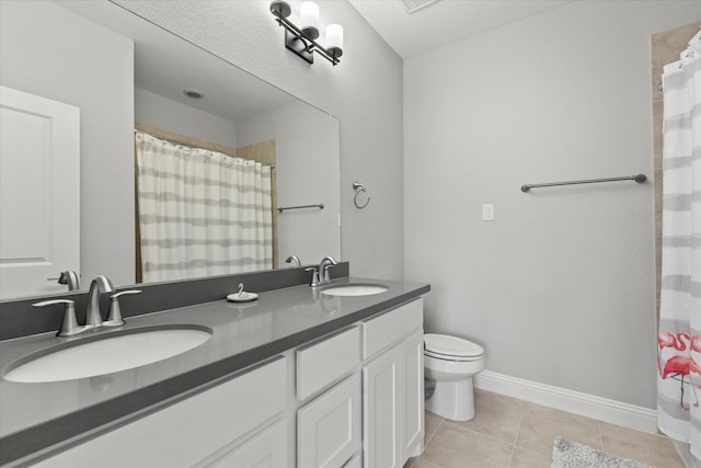 bathroom featuring tile patterned floors, toilet, double vanity, and a sink