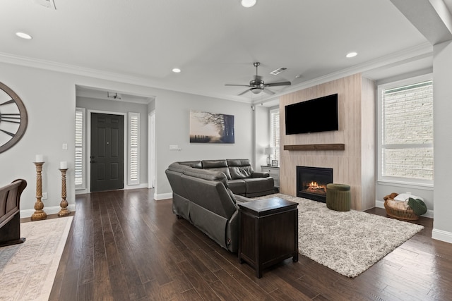 living room with visible vents, dark wood-style flooring, a fireplace, and crown molding