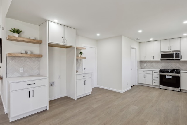 kitchen featuring stainless steel microwave, range with gas stovetop, light wood-style flooring, white cabinetry, and open shelves